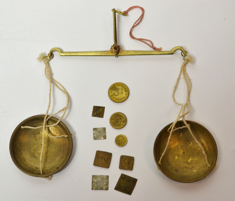 A disassembled hanging balance scale with various weights laying between the pans