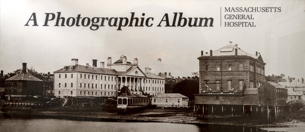 ca. 1856 black and white photo of three buildings on the wars egg. "A Photographic Album: Massachusetts General Hospital" is superimposed on the top