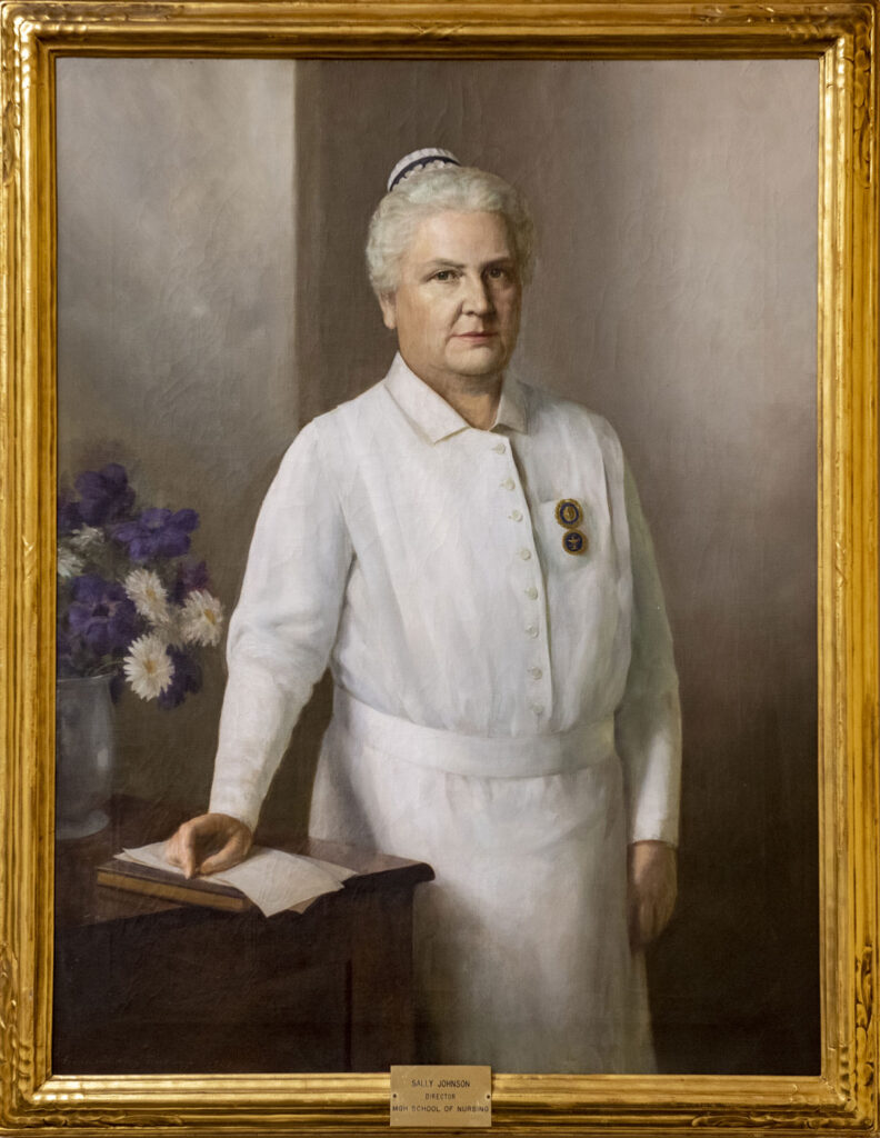 painting of white-haired woman in a nurse's uniform, with two medallions on the left breast pocket. Her right hand is resting onan open book and some papers.