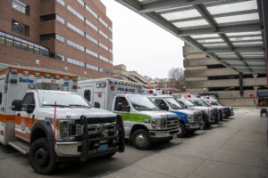 color photo of ambulances lined up in front of hospital