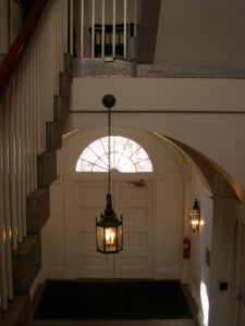 view from landing, looking down at the entryway door and lantern suspended overhead