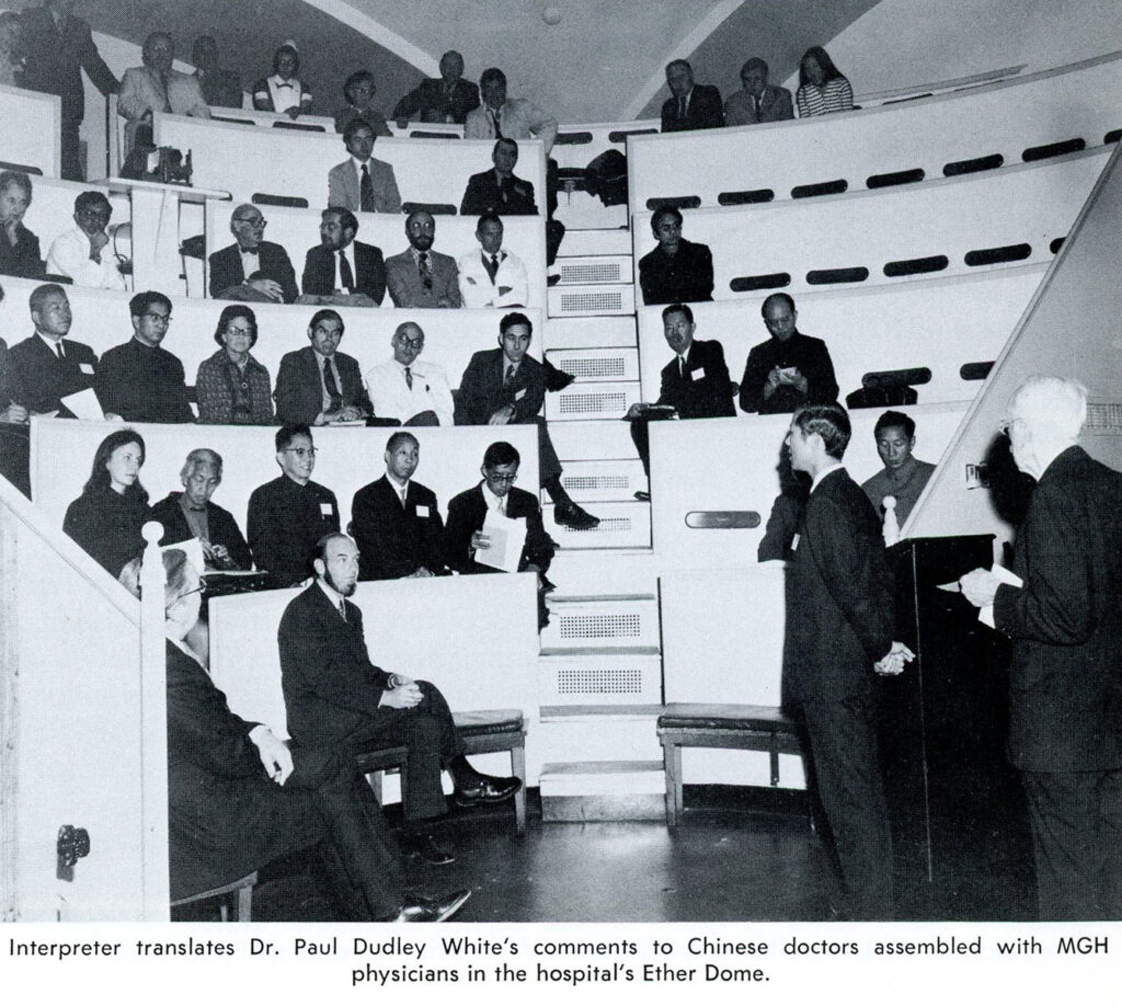 A group of doctors listening to a presentation, seated in the tiered seating of a former operating theatre