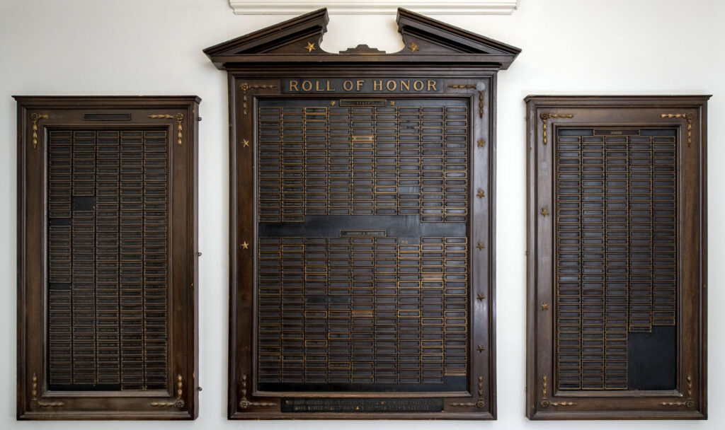 Three wall-mounted plaques with several names listed